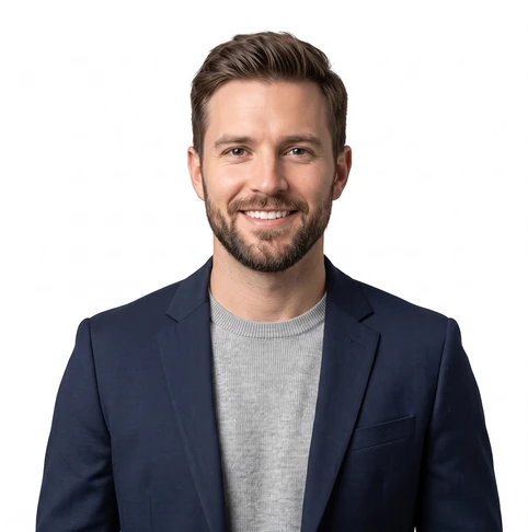 Smiling man in a navy blazer and light gray sweater against a white background (professional headshot).