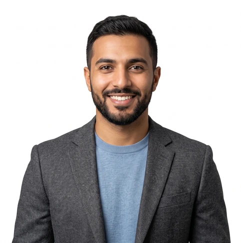 Smiling man in a gray blazer and light blue sweater, portrait against a white background.